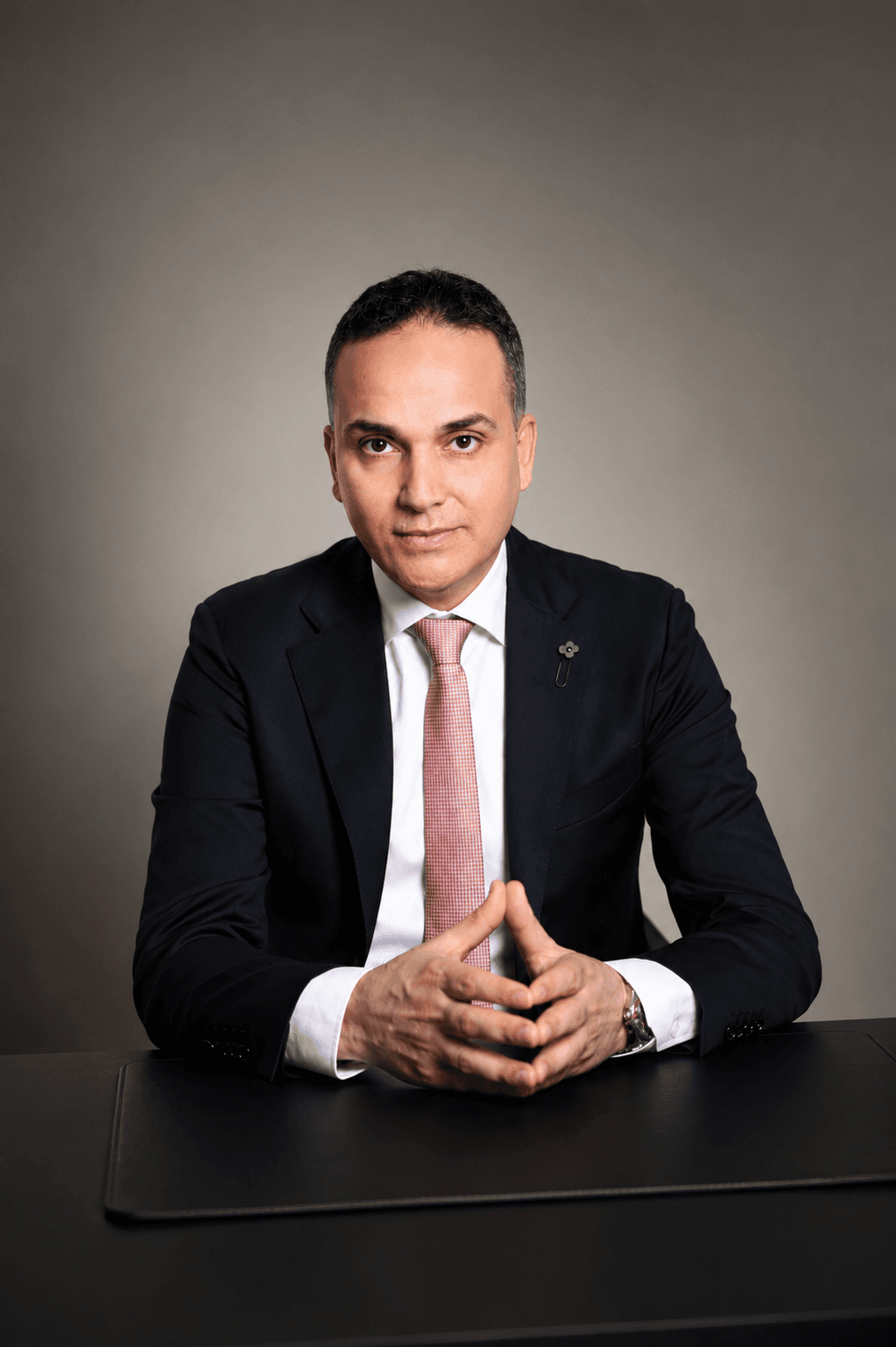 Ahmed Gadalla, founder of Alushibe, in a dark suit seated at a desk