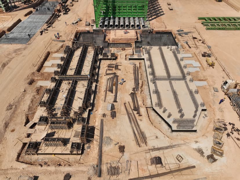 erial drone view of Tosyali Sulb steel plant construction site in Benghazi showing rebar foundations, formwork, and industrial steel structures.